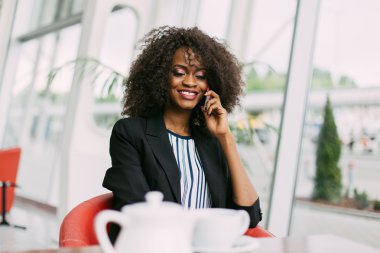 Café'de cep telefonu üzerinde konuşurken ve gülümseyen neşeli genç kadın portresi kapatın