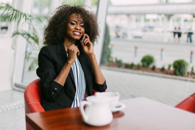 Kafede dinlenen ve telefon görüşmesi yapan afrikalı genç kadının closeup portresi