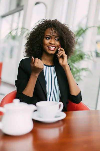 Confident young african american businesswoman talking on phone in coffee shop — Stock Photo, Image