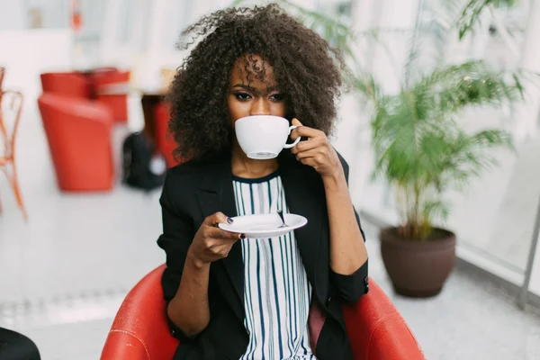 Молода афроамериканська жінка, що посміхається і насолоджується чашкою чаю. — стокове фото