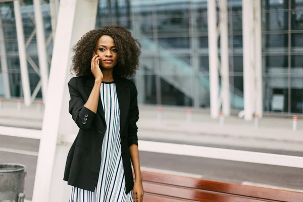 Serieuze Afro-Amerikaanse zakenvrouw die mobiele telefoon op straat gebruikt — Stockfoto