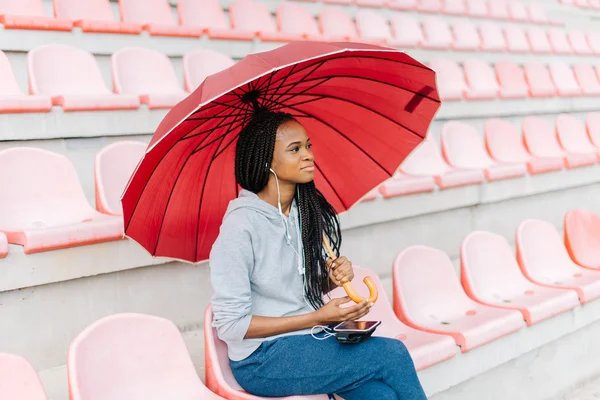 Menina americana africana feliz ouvindo a motivação da música com fones de ouvido se preparando para o treinamento cardio correr em tempo chuvoso — Fotografia de Stock
