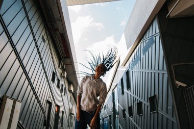 Örgüler, kentsel arka plan örgülü uçan uzun saçlı güzel Afro-Amerikan dans eden kadın