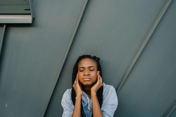 Rasakan iramanya. Charming tenang african american wanita menyentuh telinganya dan mendengarkan musik dengan mata tertutup, luar ruangan — Stok Foto