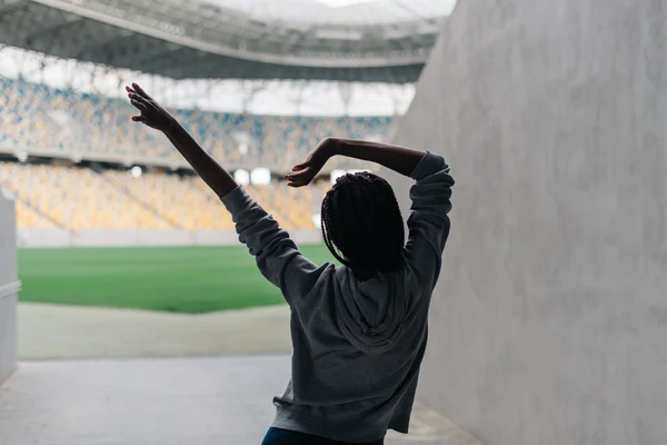 Ung attraktiv afrikansk amerikansk kvinna i grå luvtröja dansar ensam på tom stadion — Stockfoto