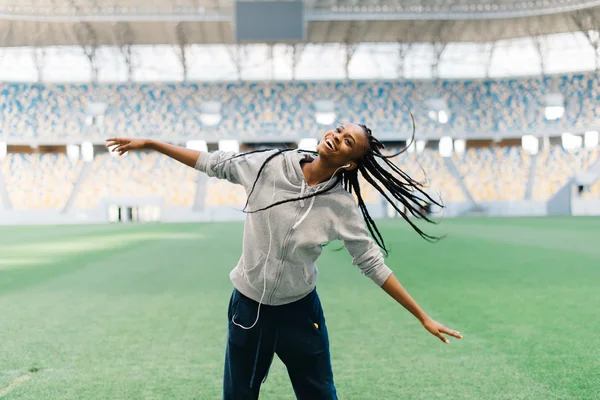 Atractiva mujer afroamericana bailando balanceando su pelo trenzado en un estadio vacío — Foto de Stock