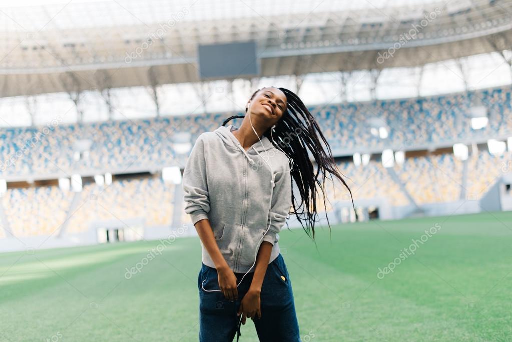 Beautiful young African American woman dancing as she throws her hair, listening to music with headphones