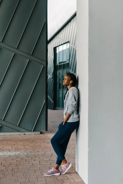 Belle jeune femme dans les écouteurs écoute de la musique, regardant vers, contre mur blanc — Photo