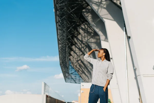 Hermosa mujer afroamericana mirando hacia el futuro con la mano en la frente, edificio moderno en el fondo — Foto de Stock