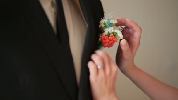 Невеста одевает женихов бутоньерки крупным планом — стоковое видео