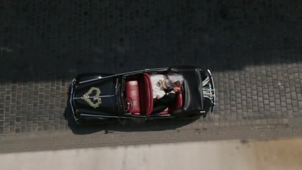 Чарівна молода пара на задньому сидінні ретро-автомобіля на міській дорозі. Вид зверху — стокове відео