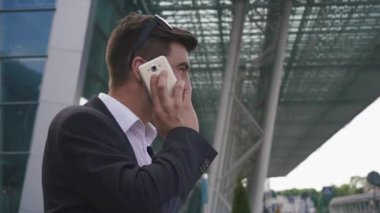 Kendine güvenen genç yakışıklı yan görünüm cam Havaalanı duvar zemin üzerine telefonla konuşan işadamı sakallı