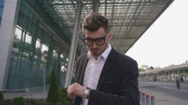 Yakın çekim yakışıklı gergin işadamı onun geri zekalı uçuş bekliyor. Modern Havaalanı arka plan