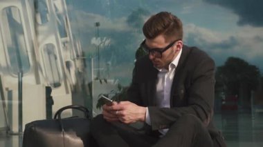 Tipik metin haber üstünde onun smartphone havaalanında çekici sakallı işadamı. Cam duvar arka plan