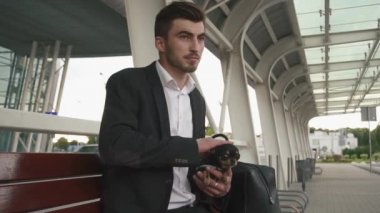 Smokinli genç ve yakışıklı bir işadamı elinde köpek yavrusuyla. Şehir arkaplanı