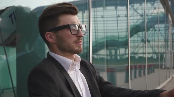 Vista lateral de un atractivo hombre de negocios se quita las gafas y estar preocupado y reflexivo mientras está de pie junto a los edificios de oficinas en una plaza clásica de la ciudad . — Vídeos de Stock