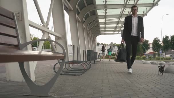 Joven hombre de negocios guapo y seguro caminando con su mascota chihuahua en el fondo urbano de la ciudad. Concepto de estilo de vida urbano — Vídeo de stock