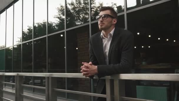 Pasajero de negocios esperando su vuelo. Modelo de hombre de negocios masculino en gafas en el fondo de pared de vidrio del aeropuerto urbano — Vídeo de stock