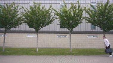 Sakallı genç yakışıklı hippi ağır çekimde büyük bir bavulla koşuyor. Şehir arkaplanı