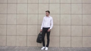 Yakışıklı işadamı iş elbisesi içinde ofis binası arka planda birini beklerken sokakta zaman kontrol. Serbest adam cebinde el ile poz.