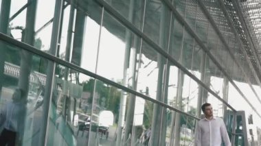 Yakışıklı işadamı gözlük ve modern havaalanı terminal cam duvar arka plan içinde bavul ile. Seyahat adam kavramı