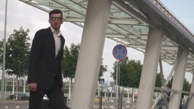 Genç yakışıklı işadamı bavuluyla karşıdan karşıya geçiyor.