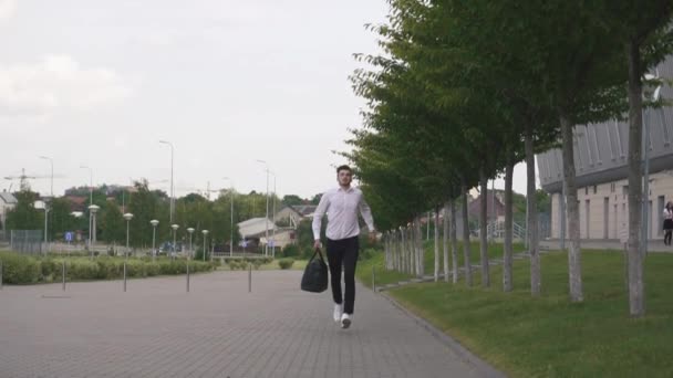 Front view of handsome businessman with beard running with big suitcase in slowmotion. Urban city background — Stock Video