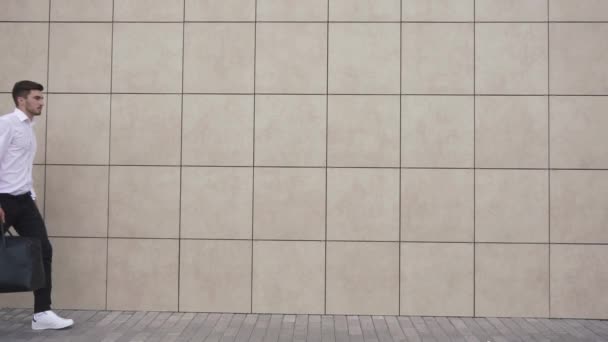 Joven empresario confiado caminando en el fondo de la pared de la oficina. El concepto de hombre de negocios moderno . — Vídeos de Stock