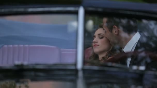 Jovem casal feliz em preto retro conversível carro do vintage, homem bonito beija suavemente menina encantadora — Vídeo de Stock