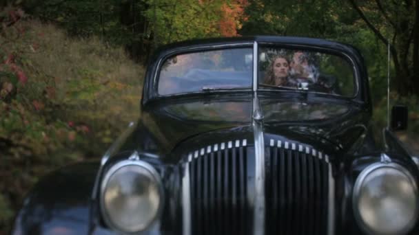 Jovem casal bonito namoro em preto retro conversível carro do vintage, homem bonito beija suavemente menina encantadora — Vídeo de Stock