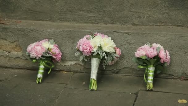 Три свадебных букета стоят у стены — стоковое видео