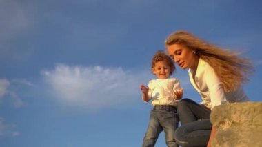 Anne ve çocuk eğleniyor'ın kıyısında bir kadeh. Anne ve çocuk suya taş atan