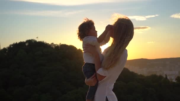 Mãe encantadora segurando pequeno filho em seus braços, natureza ensolarada como fundo — Vídeo de Stock