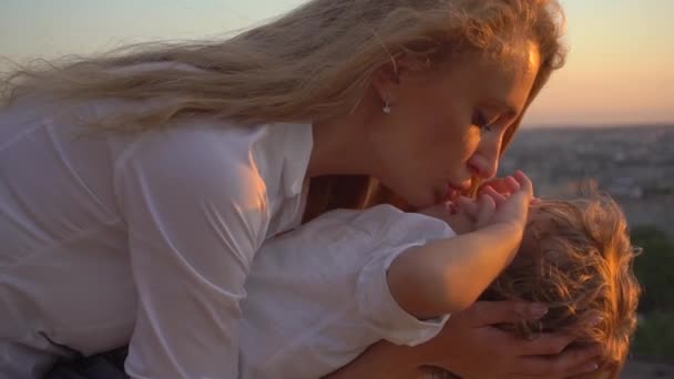 Счастливая блондинка мать держит маленького кудрявого мальчика и целует его руки, закрыть — стоковое видео