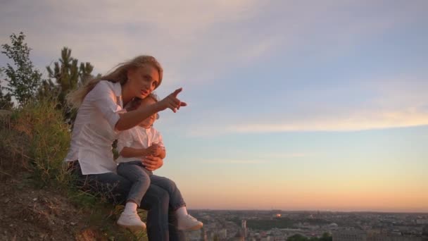 Una hermosa madre rubia disfruta pasar tiempo con su hijo y explorar cosas nuevas en la naturaleza — Vídeo de stock