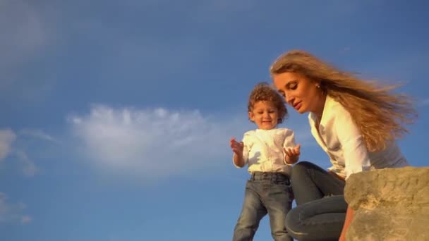 Tiro de mãe e criança se divertindo na costa. Mãe e filho jogando pedras na água — Vídeo de Stock