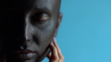 Kapanış ve açılış onun güzel yeşil gözleri, mavi arka plan siyah sanat makyaj, genç bir bayanla sürrealist yarım yüz portresi