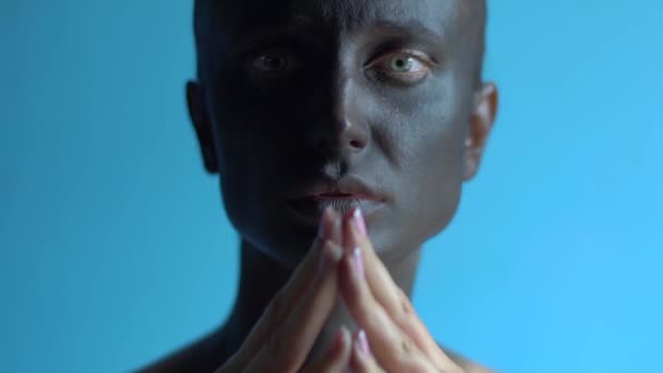 Close-up green eyed mysterious woman with artistic black make-up on her face, holding hands forming a triangle by her face and looking to the camera — Stock Video