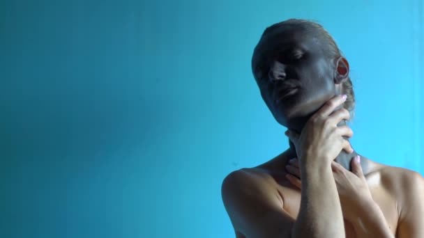 Young black painted skin woman posing over blue background. Hands strangle her slender neck. — Stock Video