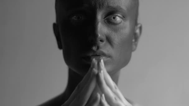 Retrato en blanco y negro de cerca de una joven mujer de piel pintada de negro cogida de la mano cerca de la cara y mirando a la cámara — Vídeo de stock