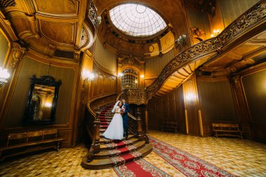 Büyüleyici gelin ve yakışıklı zarif damat şaşırtıcı vintage iç bir arka plan üzerinde birbirlerine tutarak