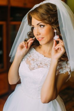 Düğün dekorasyonbüyüleyici gelin portresi. Güzel genç kadınlar küpelerini gösteriyor