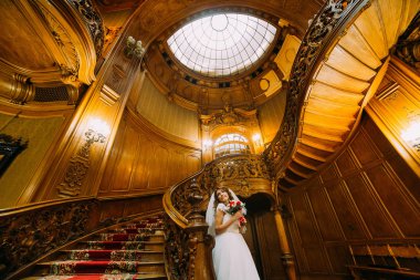 Kırmızı ve beyaz güller ile sevimli bir buket tutan gelinlik güzel gelin çarpıcı vintage ahşap iç arka planda poz