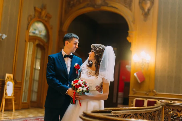 Noiva encantadora e belo noivo elegante perto de balaústre de madeira velha com o fundo do interior de luxo — Fotografia de Stock