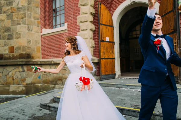 Novia feliz y novio saliendo de la iglesia después de una ceremonia de boda tradicional — Foto de Stock