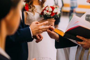 Rahip kilisede düğün töreninde bir damat el altın yüzük koyarak