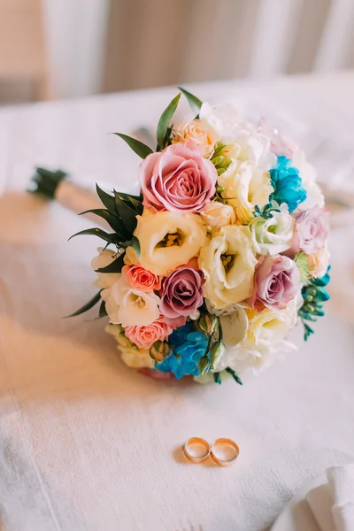 Close-up de buquê de noiva com par de anéis de casamento dourados — Fotografia de Stock
