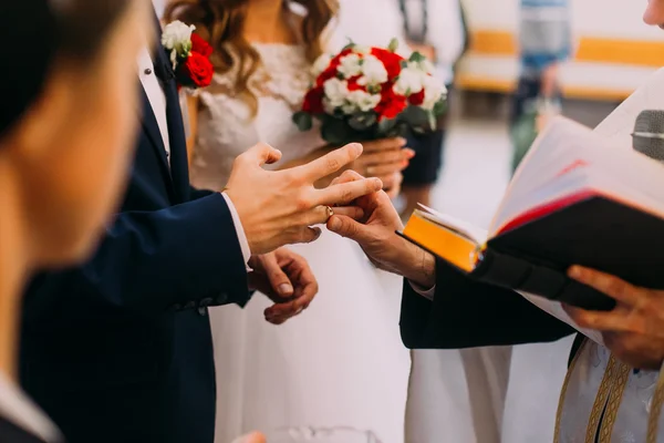 Prêtre mettre une bague d'or sur une main de marié lors de la cérémonie de mariage dans un style traditionnel — Photo