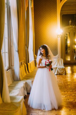 Şirin bir buket kırmızı ve beyaz gül pencere vintage ahşap iç arka plan üzerinde yakın poz ile tutarak gelinlikle güzel gelin