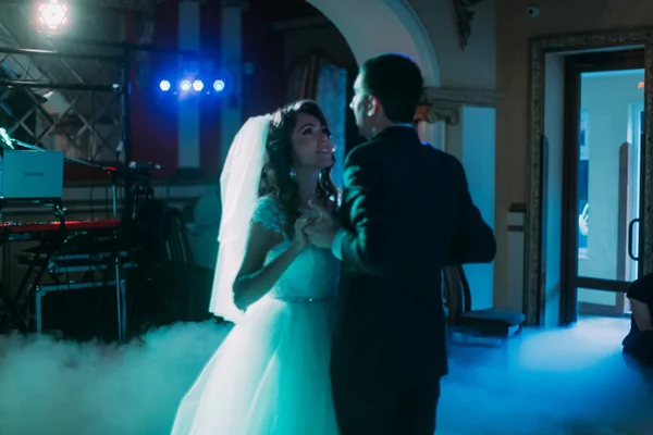 Primeira dança do feliz casal recém-casado. O salão é coberto com fumaça branca e preenchido por luzes azuis — Fotografia de Stock